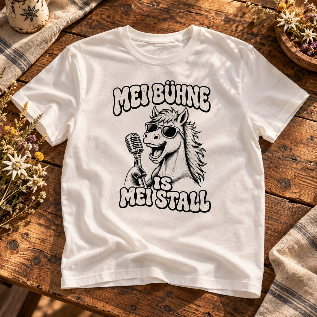 Weißes Pferdebua-Herrenshirt mit Pferd, Sonnenbrille, Mikrofon und „Mei Bühne is mei Stall“ auf einem Holztisch