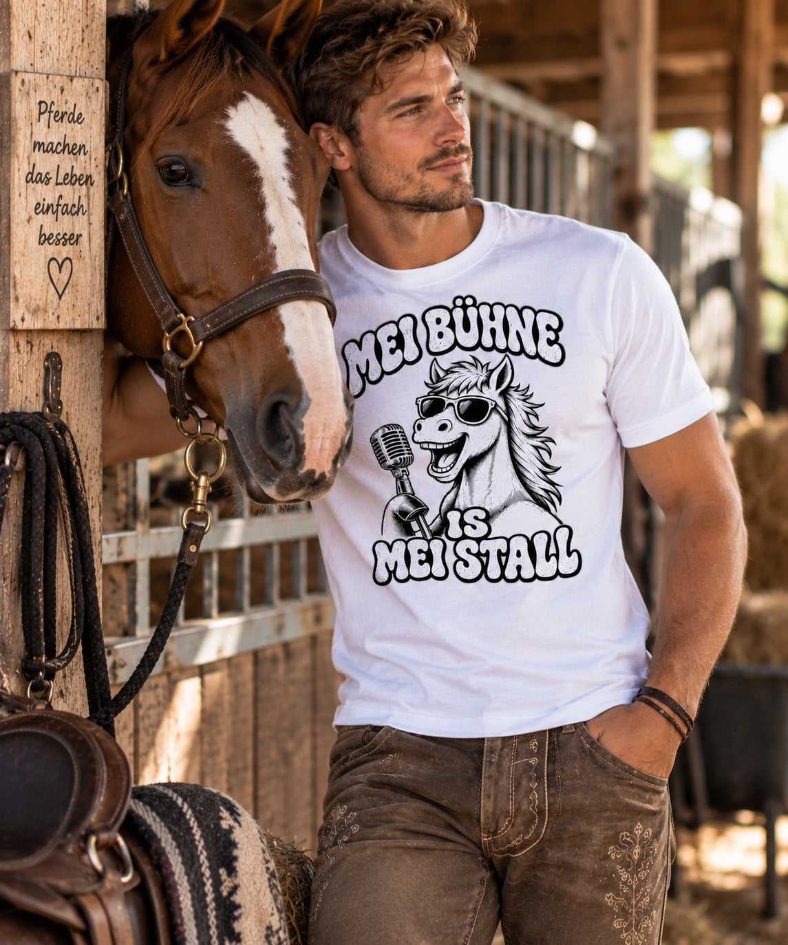 Mann trägt weißes Pferdebua-Shirt mit Pferdemotiv neben einem Pferd im Stall