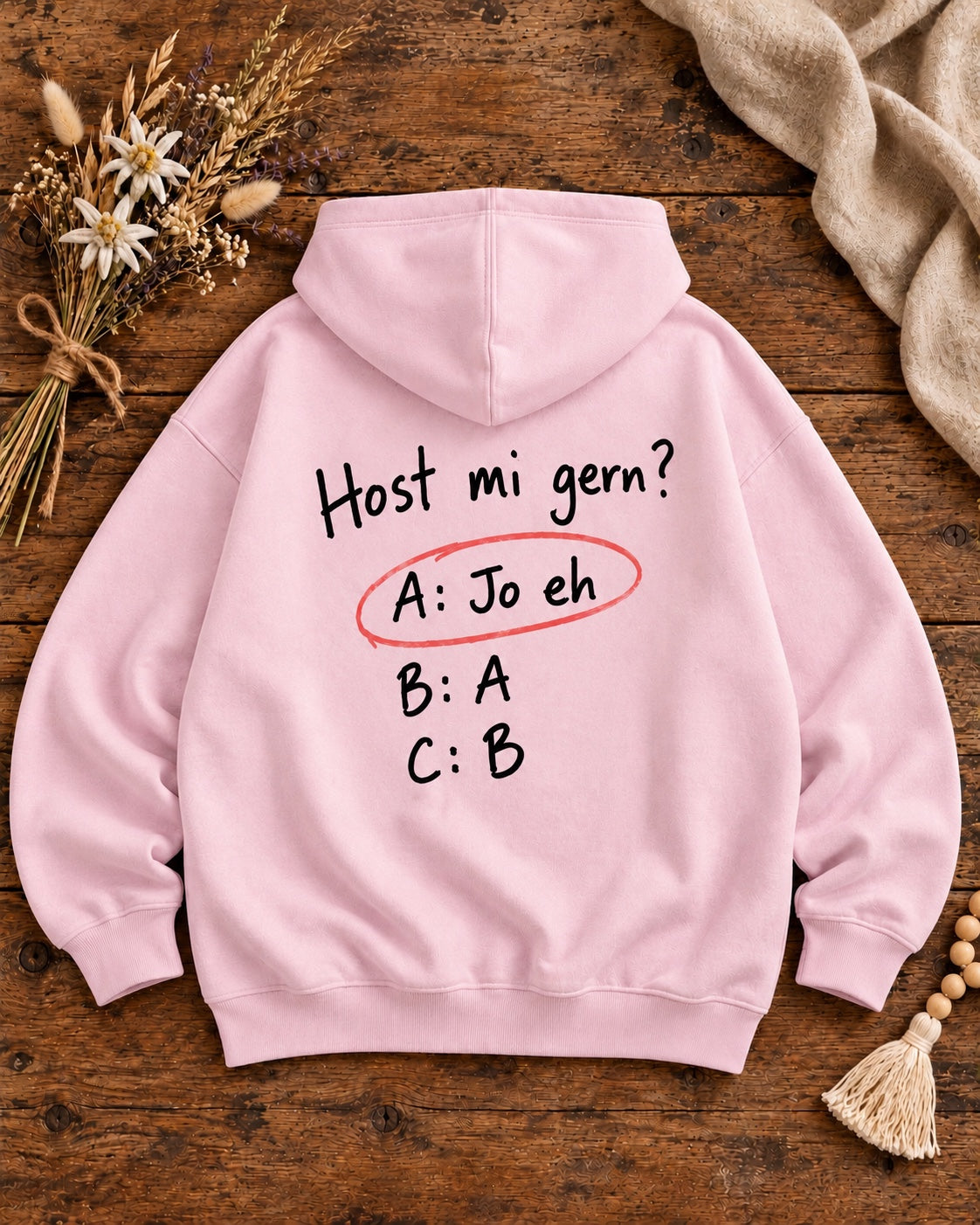 Rosa Damen Hoodie Host mi gern – Rückenansicht auf Altholztisch