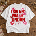 Weißes Damen Oversize-T-Shirt mit rotem Schriftzug I bin ned wia de ondan – zum Glück und Kussmundmotiven auf Holztisch