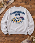 Damen Oversize-Rundhalspullover Kaiserschmarrn Club in Grau meliert auf Altholztisch – Rückseite