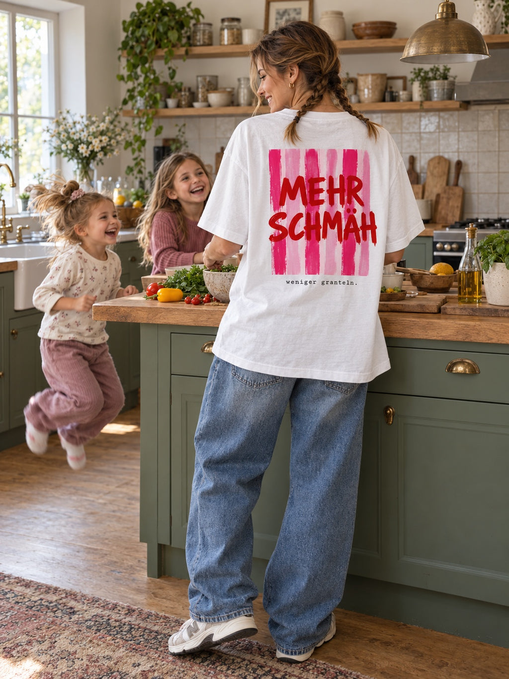Damen Oversize-T-Shirt Mehr Schmäh – weniger granteln in Weiß am Model mit Baggy Jeans in der Küche