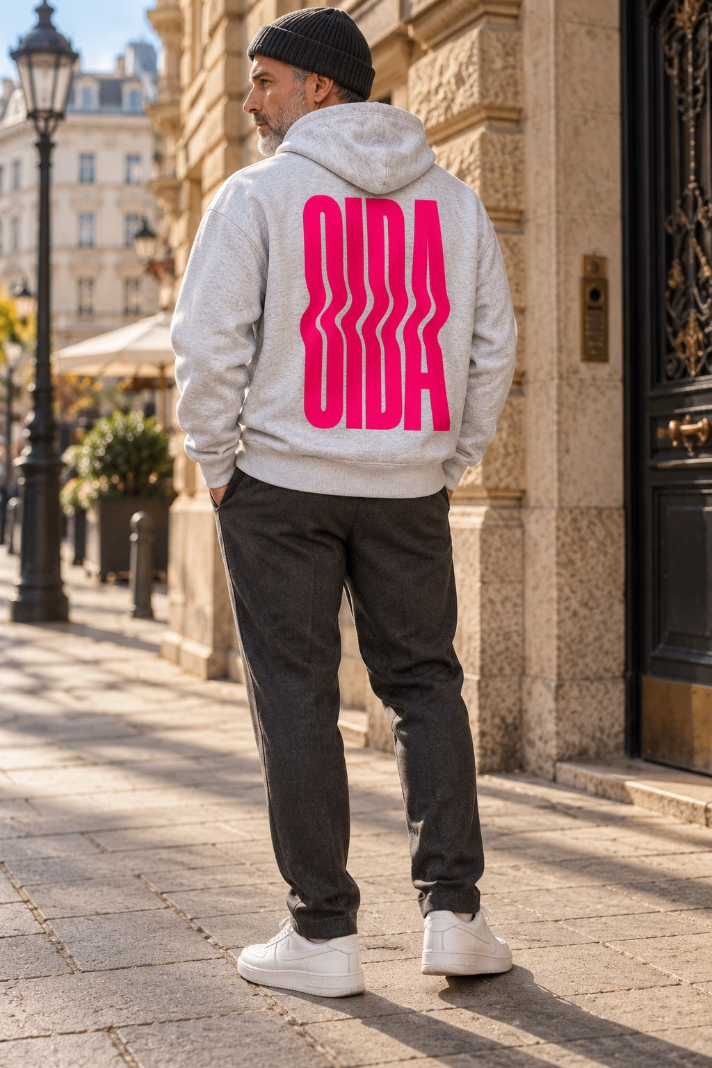 Grau melierter OIDA Hoodie mit pinkem Rückenprint am Model in der Stadt